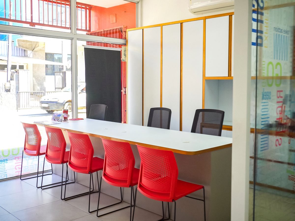 Bancada de convivência com banquetas vermelhas e divisória de vidro