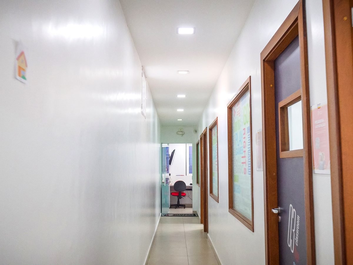 Corredor interno da unidade, com portas de madeira das salas de aula