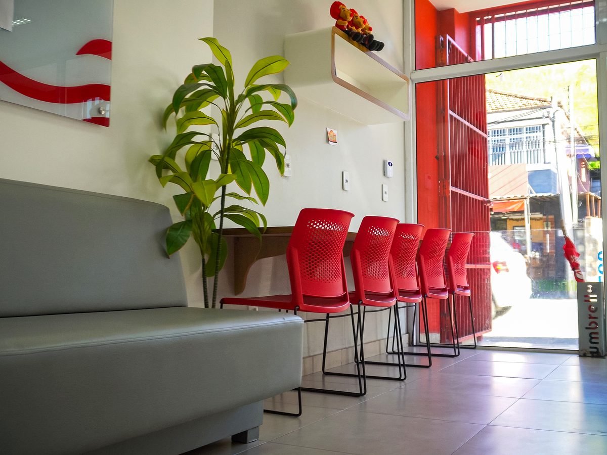 Sala de espera da unidade, com sofá, planta e banquetas